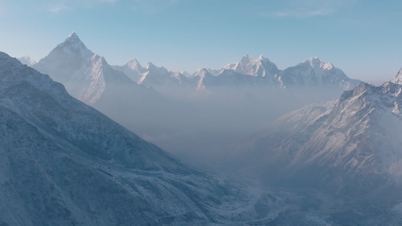 Aerial drone view of Everest Base Camp trek in Khumbu, Nepal. Morning snowfall and sunlight radiate spiritual energy across Ama Dablam and majestic Himalayan ranges under a dreamy clear blue sky