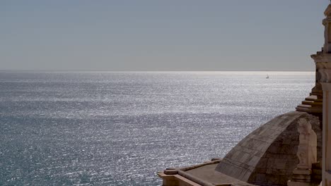 Beautiful-summer-scenery-with-sparkling-ocean-and-single-sail-ship-from-roof