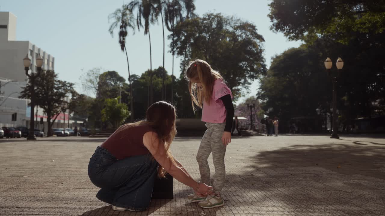 Mother helping her daughter with her shoes in a park