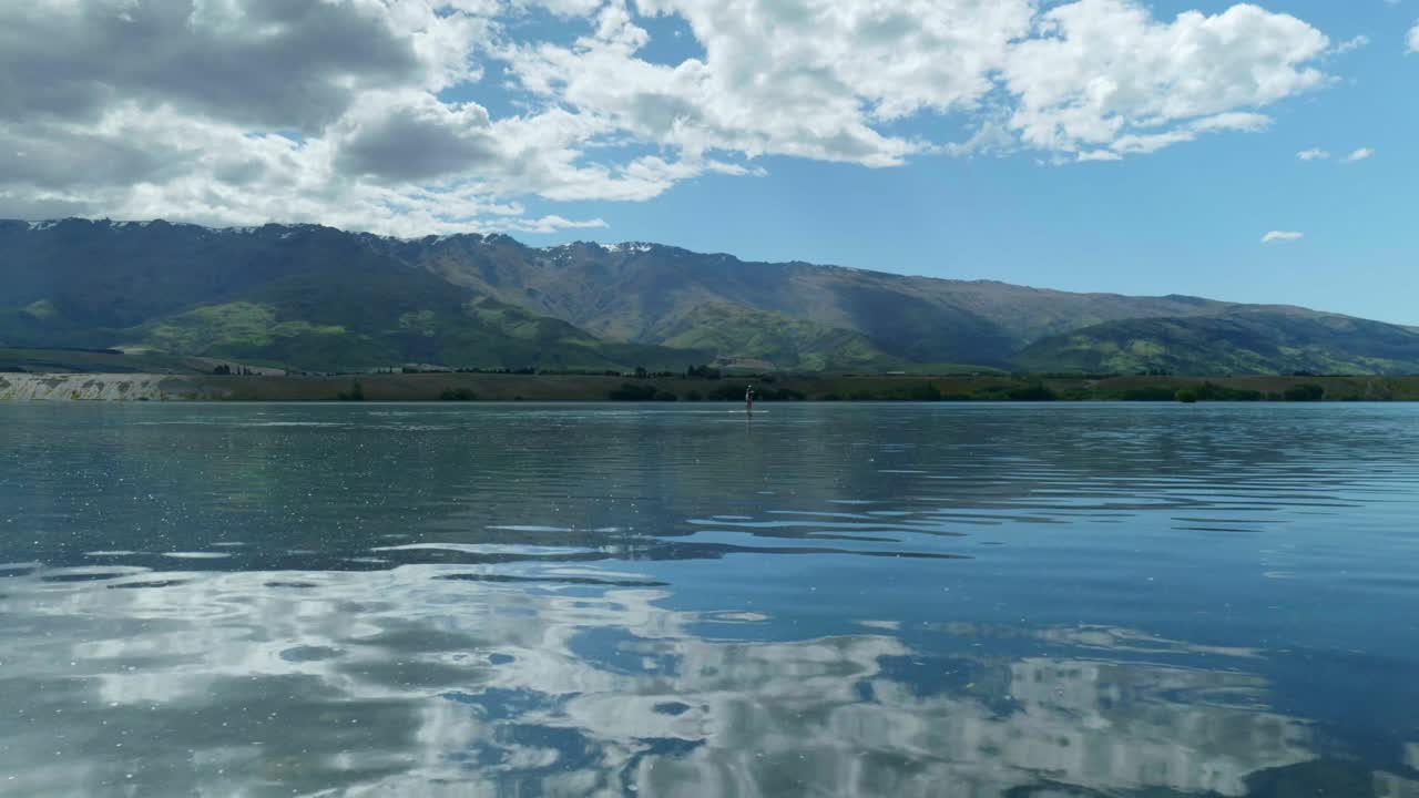 спокойное приключение: гребчик на озере с горами на заднем плане, в захватывающих кадрах