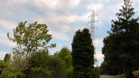 Lapso-De-Tiempo-De-Una-Torre-De-Pilón-De-Energía-De-Alto-Voltaje-Que-Se-Eleva-Por-Encima-De-Los-árboles-En-Un-Día-Soleado