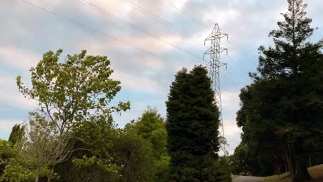 lapso de tiempo de una torre de alta tensión que se eleva por encima de los árboles en un día soleado