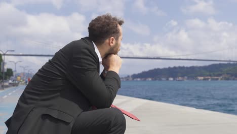 Thoughtful-businessman-in-suit-by-the-sea-in-the-city.