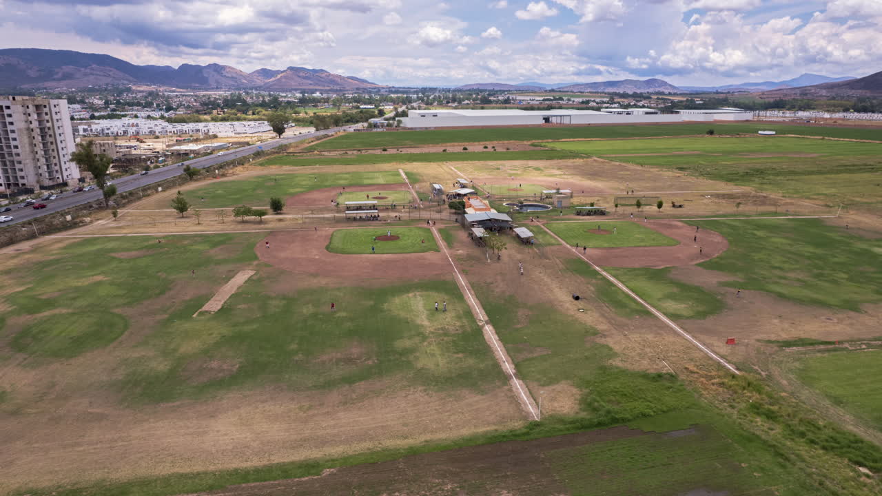 hiperlapso con una vista del horizonte de la concurrida avenida y los campos de béisbol en juego, la cámara orbita alrededor de los campos, con nubes en la distancia