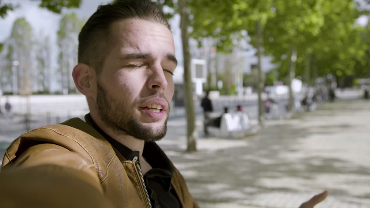 un joven blogger moreno guapo grabando un video al aire libre.