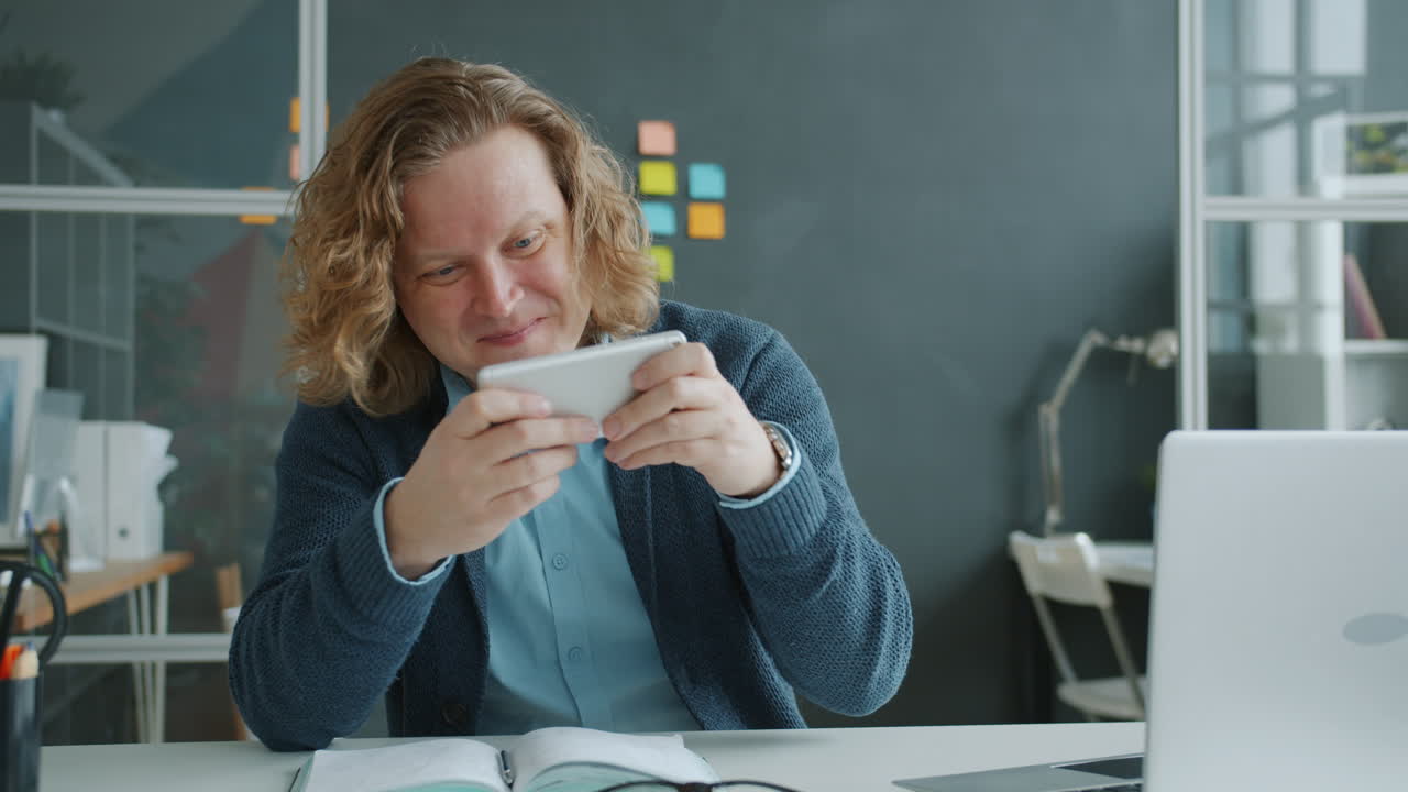 Man playing game on phone in office