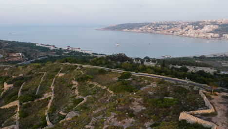 Drone-shot-passing-the-Fort-Saint-Agatha,-toward-the-sea,-golden-hour-in-Malta