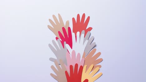 close up of hands together made of colourful paper on blue background with copy space