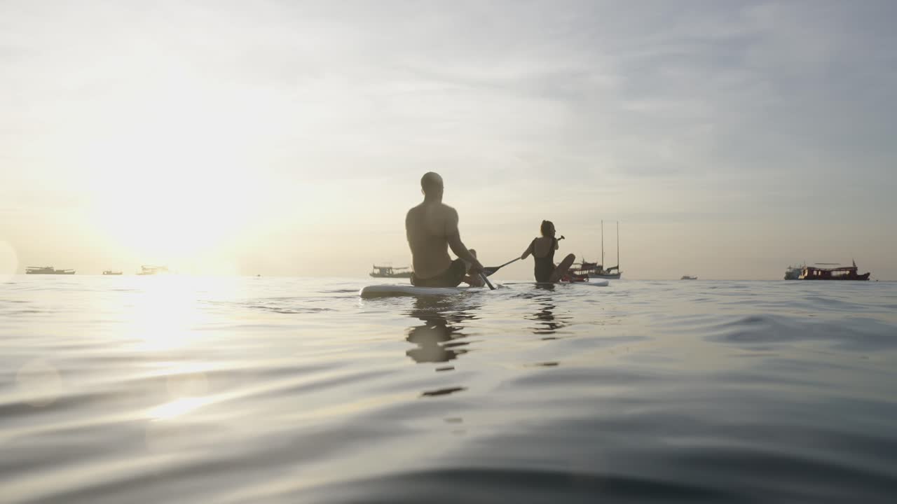 People Paddleboarding on Calm Water at Sunset