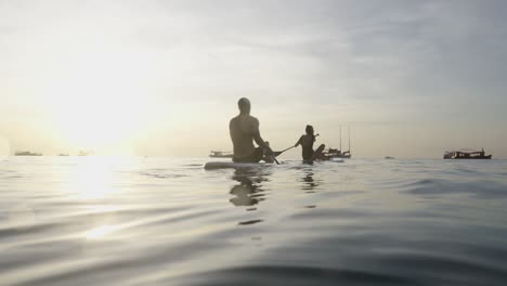 people paddleboarding on calm water at sunset