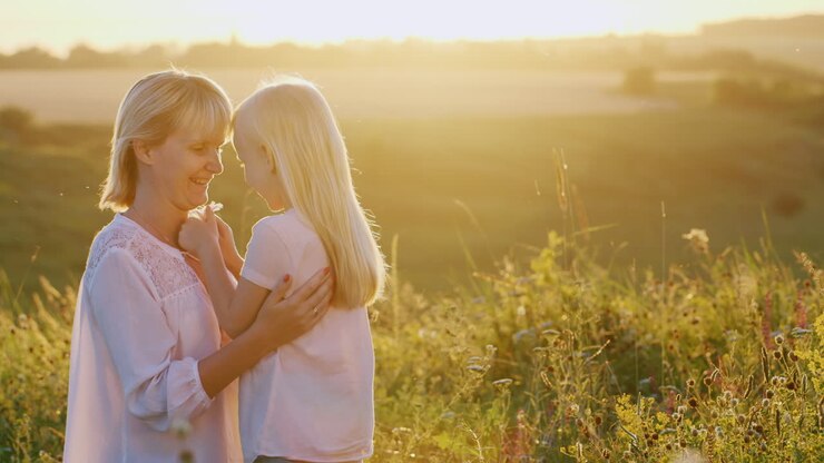 Blonde Mutter und Tochter unterhalten sich auf dem grünen Rasen.