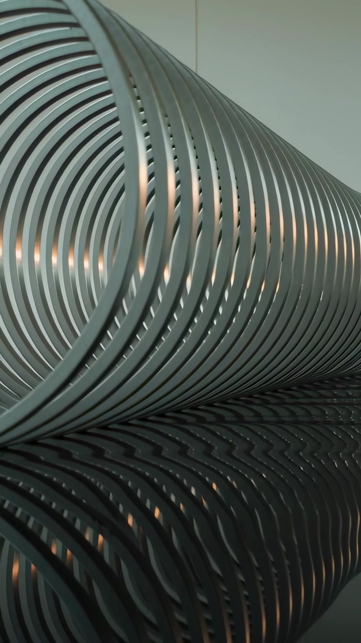 Vertical video: Moving cam tilting metal coil, showing rings on shiny table, revealing pattern