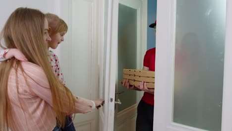 el repartidor con cajas de pizza suena en el timbre de la puerta, la mujer con el niño abre las puertas, paga en efectivo por el pedido