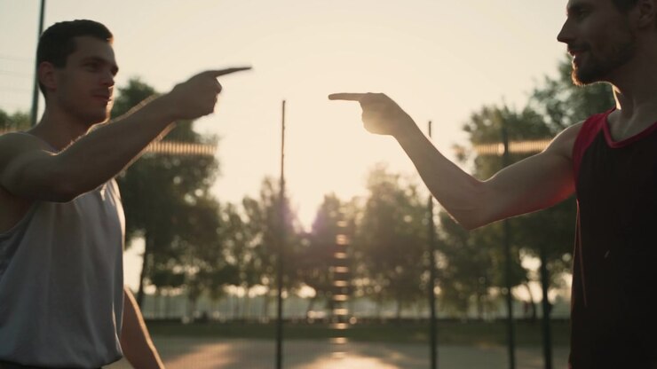 Cordiale saluto tra due amici maschi sorridenti in un parco al tramonto