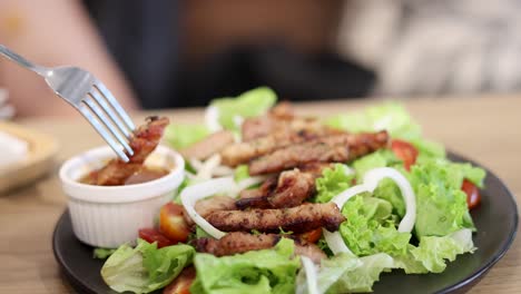 fork dipping meat into sauce on salad