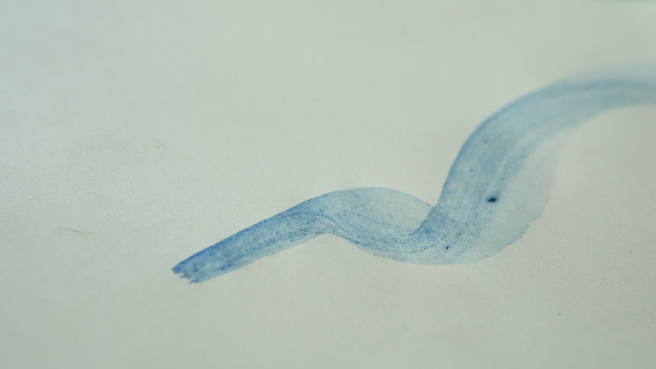 アーティストは絵筆と水彩で青いブラシストロークを描きます