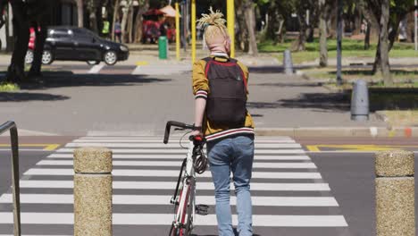 Albino-african-american-man-with-dreadlocks-crossing-street-with-bike