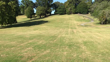 Upward-pan-of-the-green-lawn-surrounded-by-trees-and-a-pathway-at-the-Monte-Cecilia-Park-in-Auckland