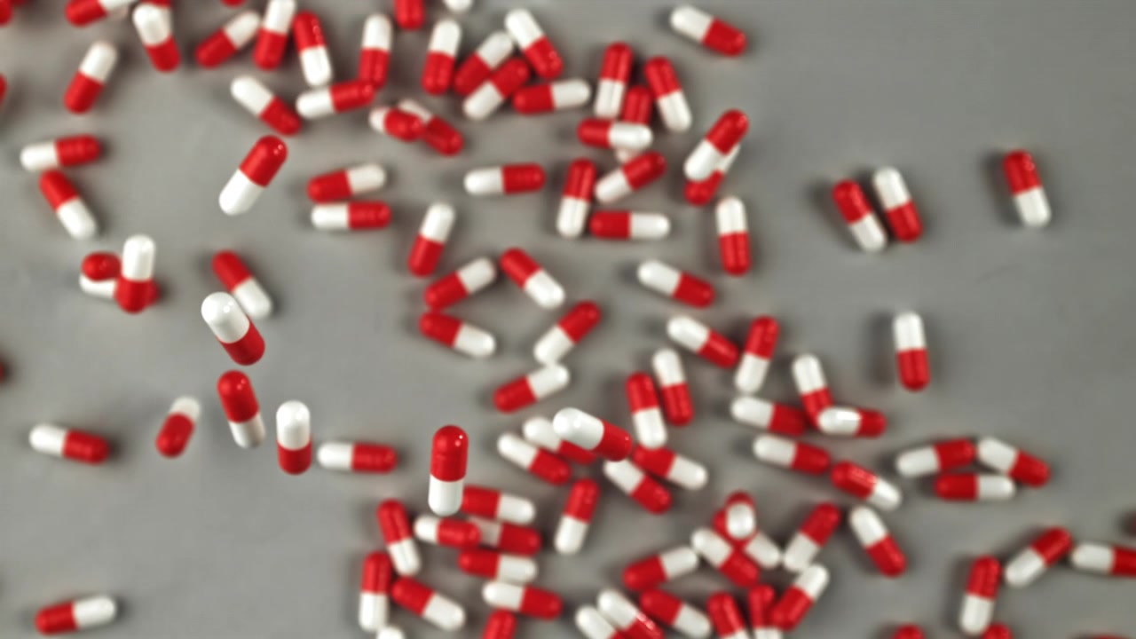 Capsule mediche rosse e bianche che cadono al rallentatore