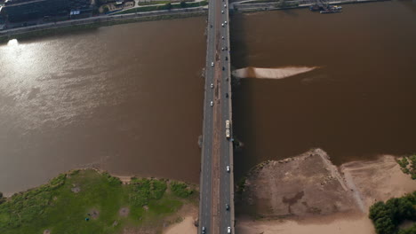 High-angle-view-of-vehicles-driving-over-Vistula-river-on-Poniatowski-Bridge.-Forwards-fly-above-transport-infrastructure.-Warsaw,-Poland