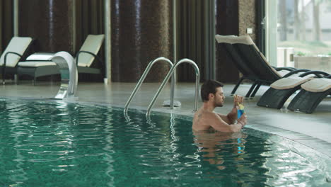 Attractive-man-drinking-cocktail-at-luxury-pool.-Guy-relaxing-with-alcohol