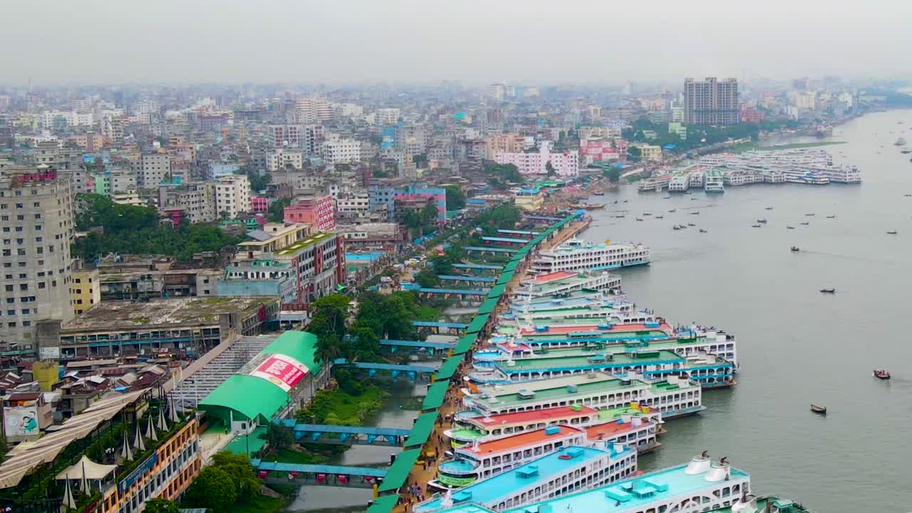 Veduta aerea del vivace terminal navale di Sadarghat a Dhaka lungo il fiume Buriganga, con barche colorate allineate su uno sfondo grigio