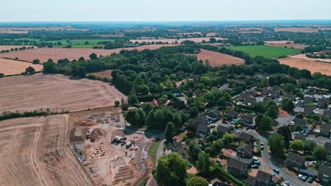 Luftaufnahmen-Des-Kleinen-Dorfes-Acton-In-Suffolk,-Umgeben-Von-üppigem-Ackerland-Und-Goldenen-Feldern