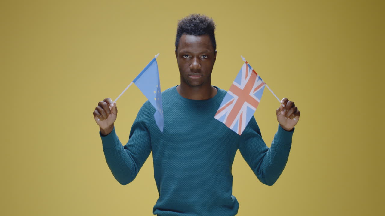 Man holds EU and UK flags, showing different expressions regarding political themes