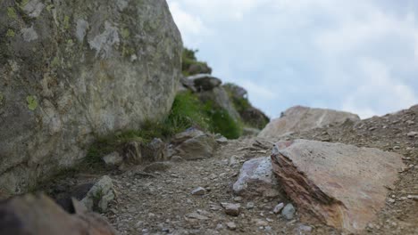 Woman-on-a-hike-wearing-sporty-outfit-walks-towards-camera,-rocky-mountain-trail