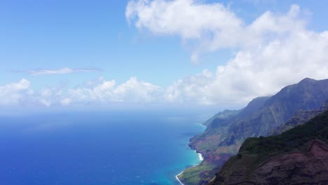 aerial tilt down looking northeast up the na pali coast. includes puffy white clouds, deep blue and turquoise water, and incredible mountain peeks seemingly rising from the ocean