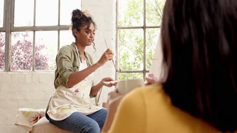 woman painting at home, smiling and chatting with friend in cozy setting