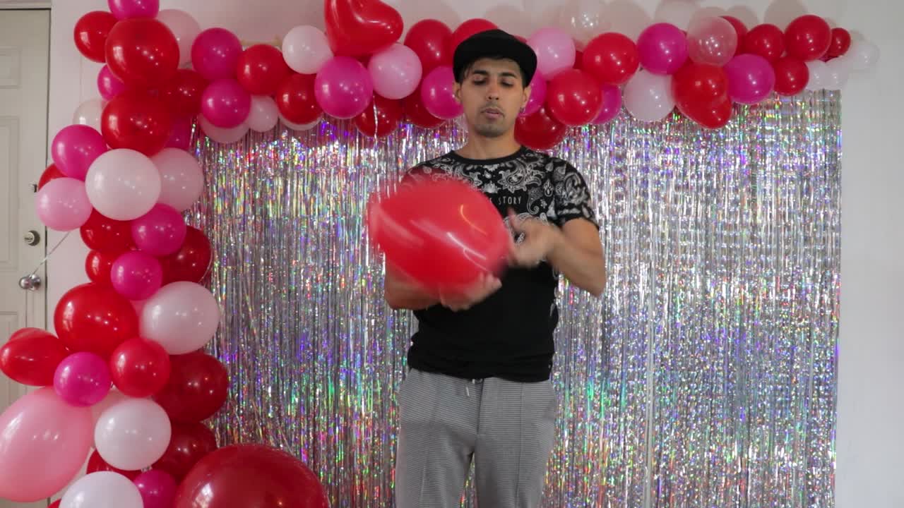 젊은 남자가 발렌타인 장식품을 위한 프로 심장 풍선을 부풀리고 있습니다.