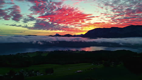 disparo de avión no tripulado panorámico sobre el campo con un fondo de cielo montañoso al atardecer en austria