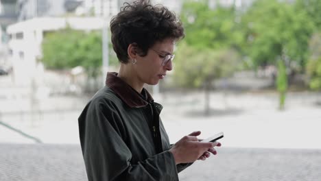 mujer caminando por la calle con un teléfono inteligente en las manos