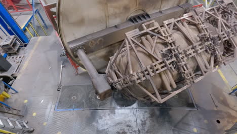 top shot of a big rusty metallurgical industrial machinery rotate from heating room to cooling fans, rotomolding process using reuse and recylcing plastic