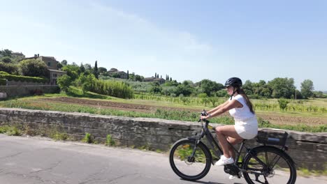 hispanic young woman enjoying an afternoon scenic bike ride along a country road in tuscany, italy