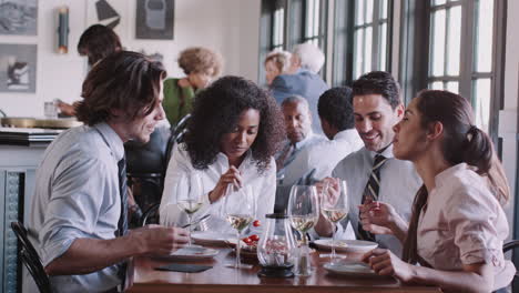 business colleagues sitting around restaurant table enjoying meal together