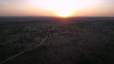 African-Serengeti-landscape-seen-at-sunset-over-horizon,-Aerial-rising-pedestal-shot