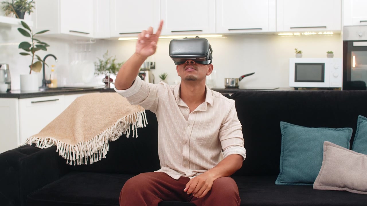 Uomo indiano con visore VR annuisce, dice "wow", muove le mani, gioca e reagisce a contenuti online con gioia.