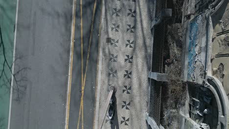 Top-down-aerial-panning-view-of-famous-Almirante-Reis-avenue-sidewalk-with-some-trees-shadows-in-Lisbon,-Portugal-at-sunrise