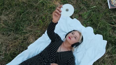 Beautiful girl lying on the grass and listening to music