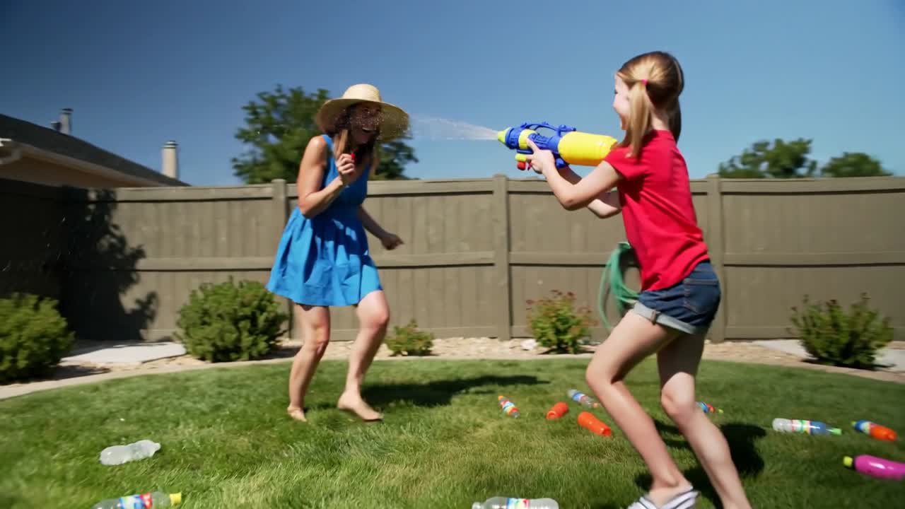 Playing woman-in-sundress and child-in-red-shirt firing blaster in yard for play holding red bottle