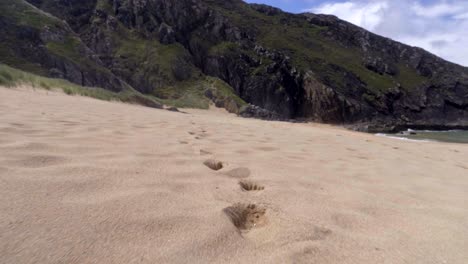 huellas en la arena de la hermosa isla de la playa de las cuevas en donegal, irlanda - toma de carro a nivel del suelo