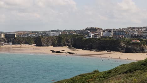 Hand-held-establishing-shot-of-Towan-beach-with-surfers-in-the-sea-at-Newquay
