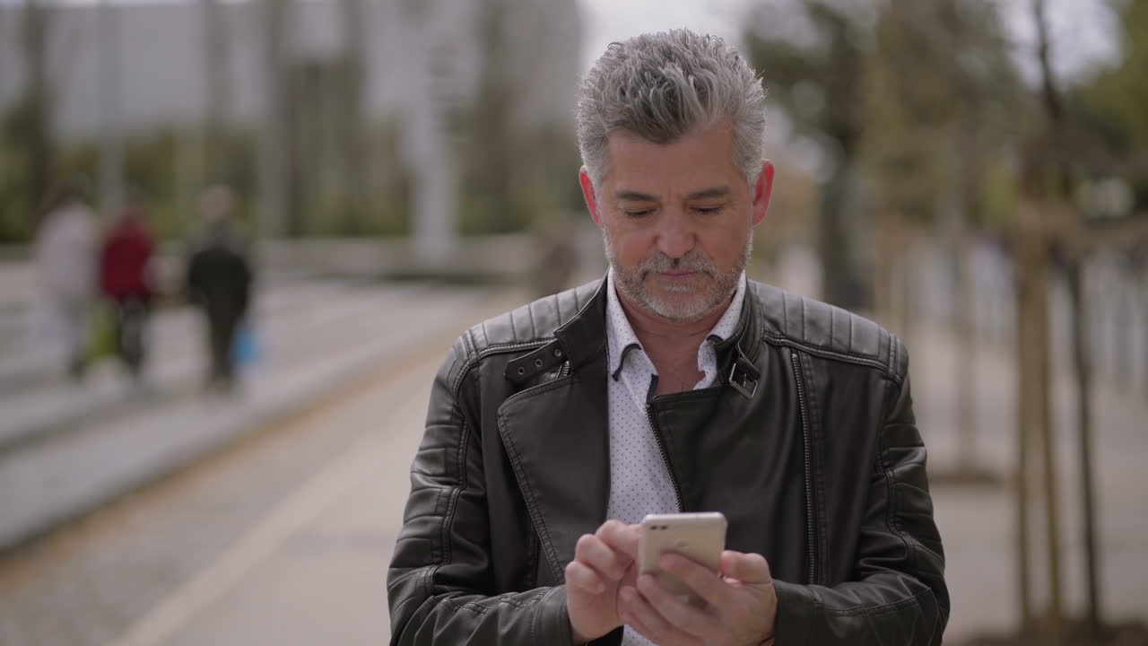 Uomo maturo concentrato che usa lo smartphone all'aperto