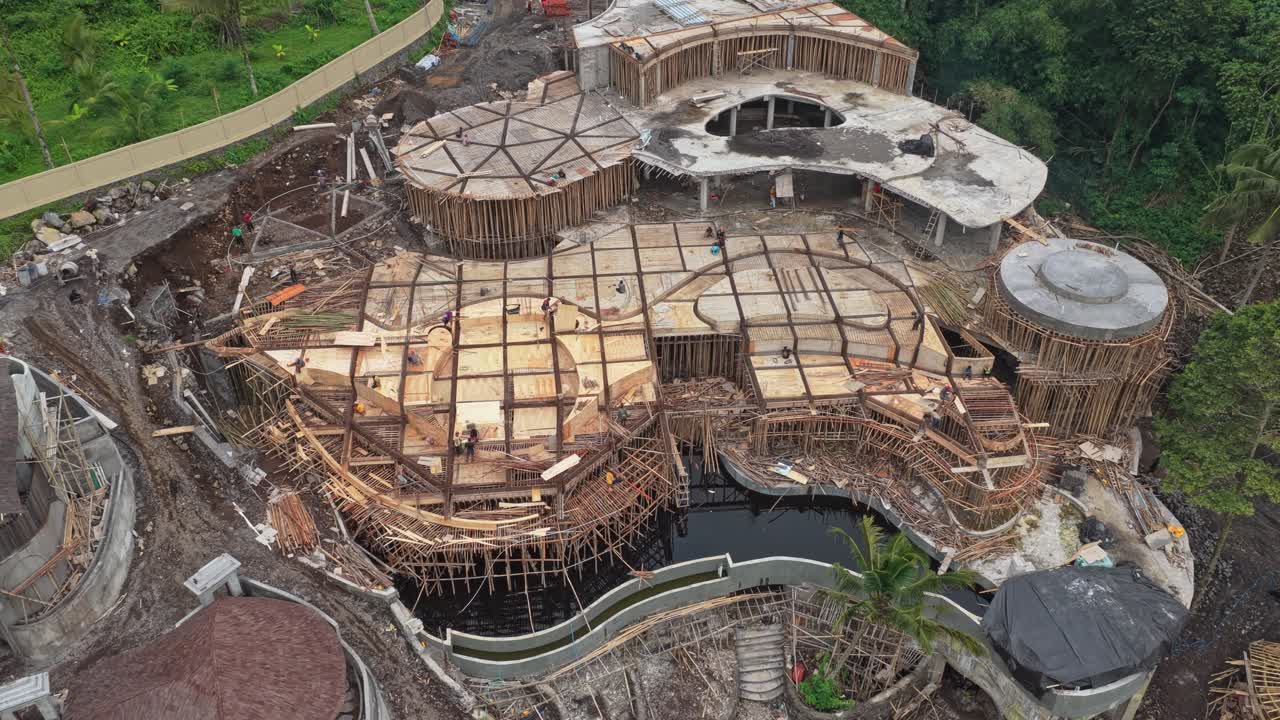 Prise de vue aérienne en plongée d'un grand bâtiment en construction au design unique, entouré d'une jungle tropicale luxuriante à Bali, Indonésie