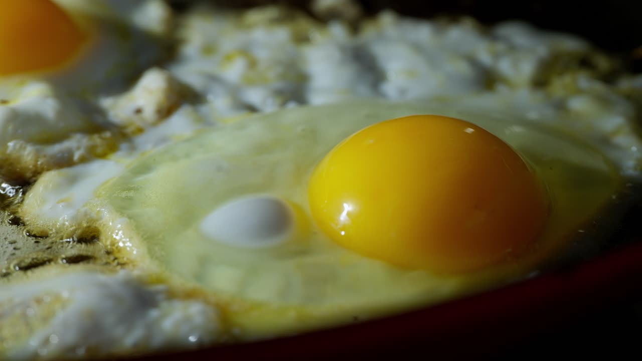 Fresh egg frying on hot buttered pan surface in real time kitchen cooking scene