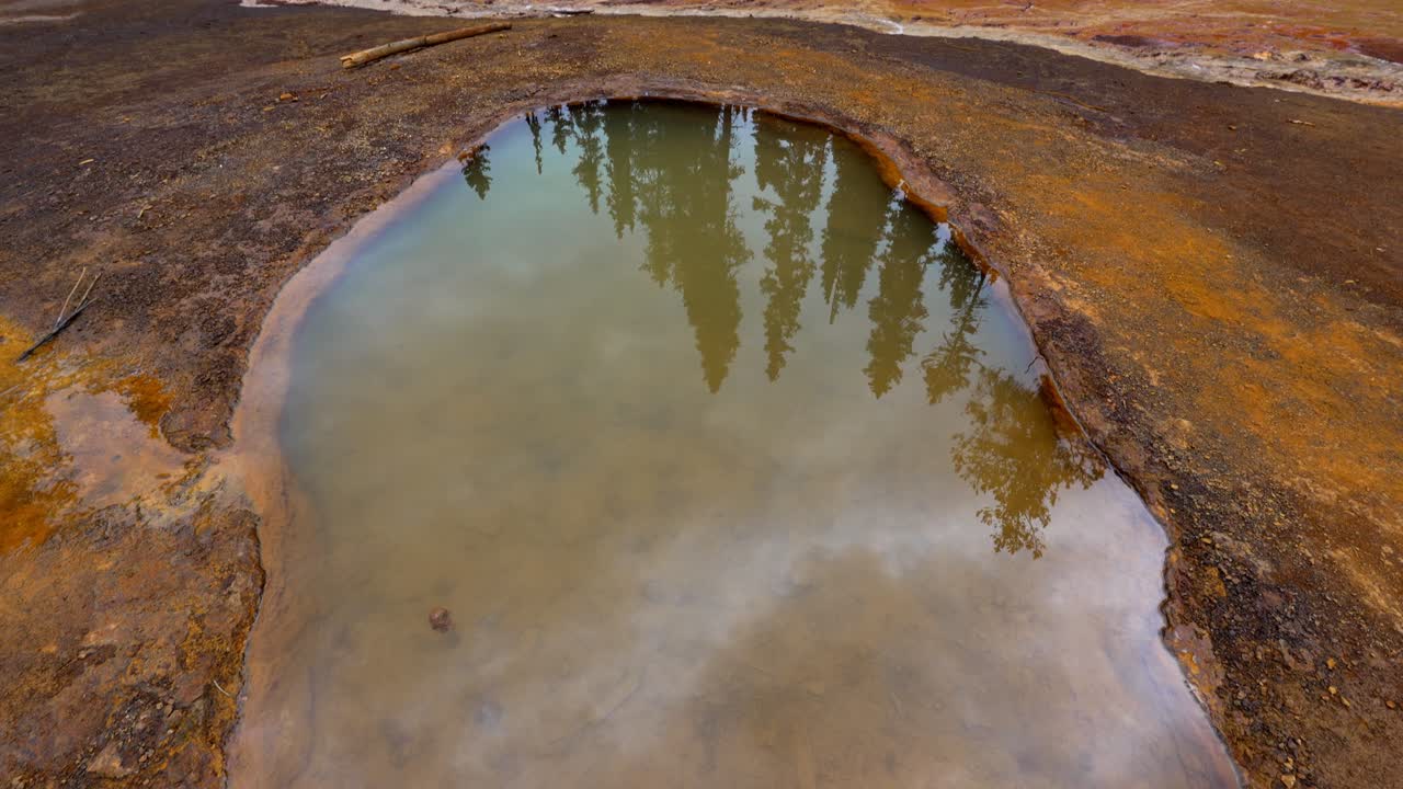 Woman standing on the colorful ochre banks of Paint Pots mineral springs in Kootenay National Park