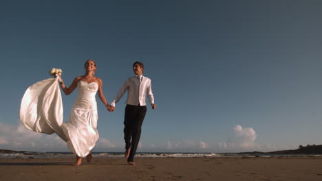 cheerful bridal couple running on the beach