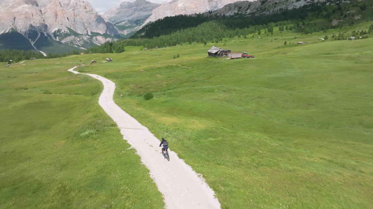 Cyclist maneuvers along winding unpaved road in Pralongia, Italian Dolomites